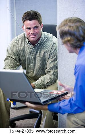 Businessmen looking at laptop in an office View Large Photo Image Stock Photography - Businessmen looking at laptop in an office. Fotosearch