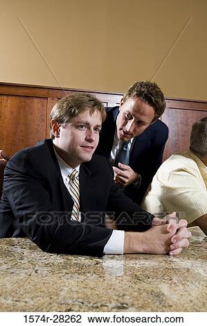 Businessmen sitting by conference table and discussing in an office View Large Photo Image Stock Image - Businessmen sitting by conference table and discussing in an office. Fotosearch
