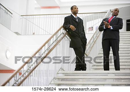 Businessmen standing on staircase in an office View Large Photo Image Picture - Businessmen standing on staircase in an office. Fotosearch
