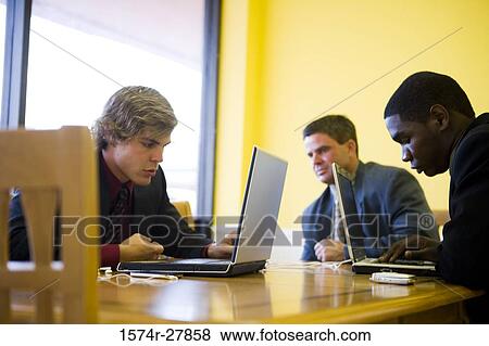 Stock Photo - Businessmen using laptop in an office. Fotosearch