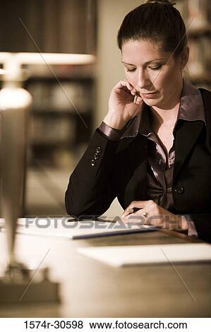 Businesswoman reading file on table in an office View Large Photo Image Stock Photo - Businesswoman reading file on table in an office. Fotosearch