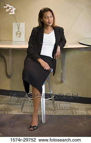 Businesswoman sitting on a stool in an office View Large Photo Image Stock Image - Businesswoman sitting on a stool in an office. Fotosearch