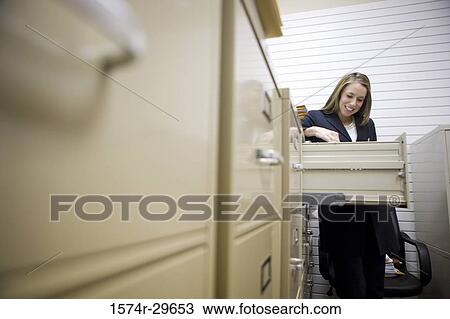 Businesswoman standing by lockers in an office View Large Photo Image Stock Image - Businesswoman standing by lockers in an office. Fotosearch