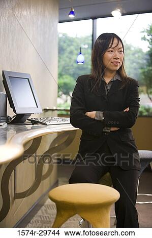Businesswoman standing in an office by computer View Large Photo Image Picture - Businesswoman standing in an office by computer. Fotosearch