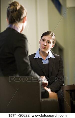 Stock Image - Businesswomen discussing in an office. Fotosearch