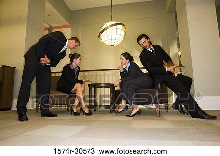 Stock Image - Businesswomen discussing while businessmen listening them in an office. Fotosearch