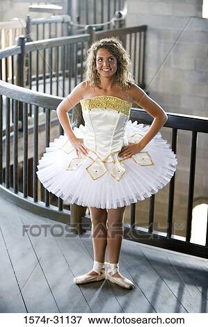 Stock Photo - Cheerful ballet dancer standing by wooden railing with hand on hip. Fotosearch
