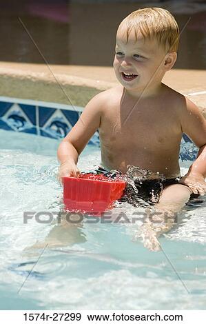Stock Photo - Cheerful boy playing with a toy in swimming pool. Fotosearch