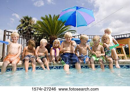 Stock Photograph - Cheerful boys and girls sitting poolside. Fotosearch