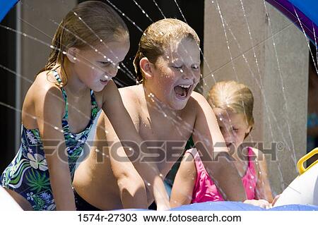 Cheerful boys and girls wetting their body in spray View Large Photo Image Stock Image - Cheerful boys and girls wetting their body in spray. Fotosearch