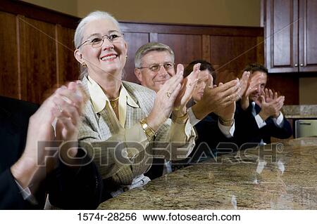Cheerful business people sitting by conference table and applauding in an office View Large Photo Image Stock Photograph - Cheerful business people sitting by conference table and applauding in an office. Fotosearch