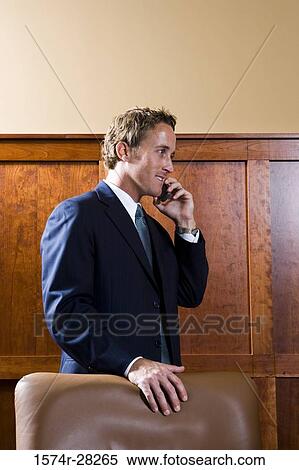 Cheerful businessman communicating on a mobile phone in an office View Large Photo Image Stock Photography - Cheerful businessman communicating on a mobile phone in an office. Fotosearch