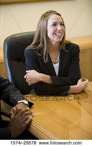 Cheerful businesswoman sitting in an office View Large Photo Image Stock Photo - Cheerful businesswoman sitting in an office. Fotosearch
