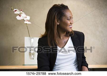 Cheerful businesswoman sitting in an office View Large Photo Image Stock Photo - Cheerful businesswoman sitting in an office. Fotosearch
