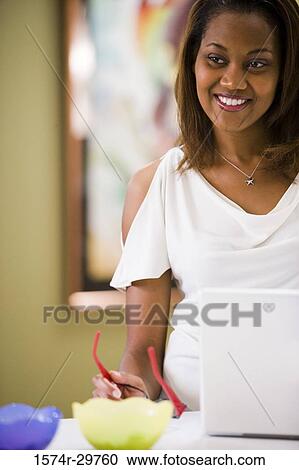 Cheerful businesswoman standing in front of a laptop View Large Photo Image Stock Image - Cheerful businesswoman standing in front of a laptop. Fotosearch