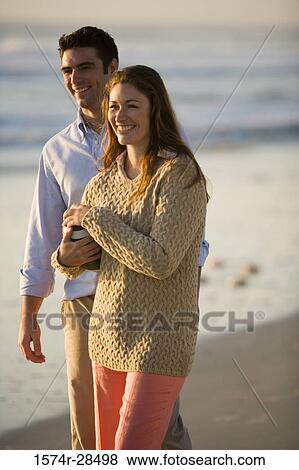 Cheerful couple standing together on a beach View Large Photo Image Stock Photo - Cheerful couple standing together on a beach. Fotosearch