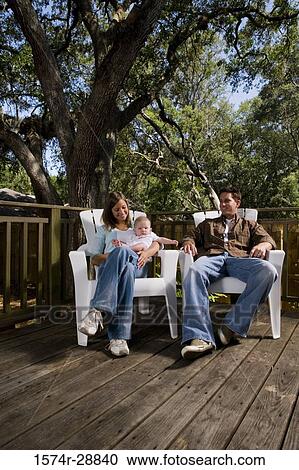 Stock Image - Cheerful family relaxing on armchairs on wooden plank. Fotosearch