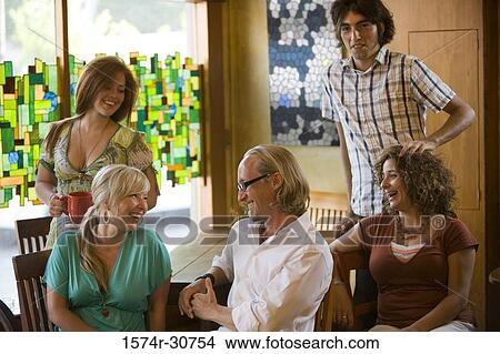 Cheerful family sitting together by table View Large Photo Image Picture - Cheerful family sitting together by table. Fotosearch