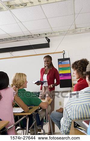 Picture - Cheerful female teacher teaching students in the classroom. Fotosearch