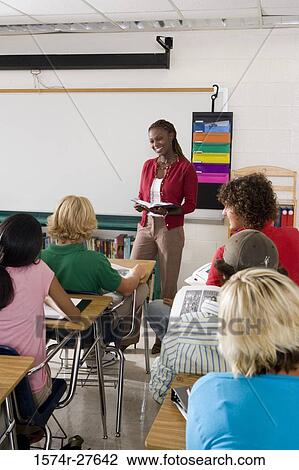 Stock Image - Cheerful female teacher teaching students in the classroom. Fotosearch