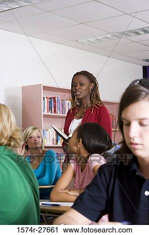 Stock Image - Cheerful female teacher teaching students in the classroom. Fotosearch