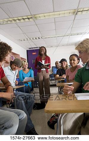 Stock Image - Cheerful female teacher teaching students in the classroom. Fotosearch