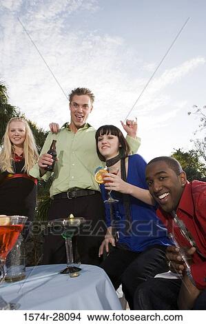 Cheerful friends enjoying wines by table View Large Photo Image Picture - Cheerful friends enjoying wines by table. Fotosearch