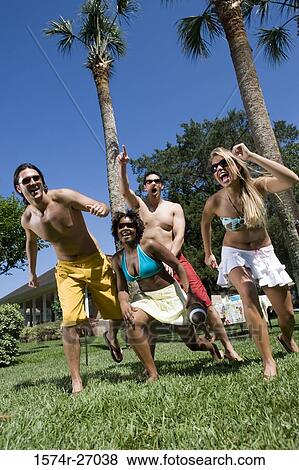 Cheerful friends playing touch football on lawn View Large Photo Image Stock Photo - Cheerful friends playing touch football on lawn. Fotosearch