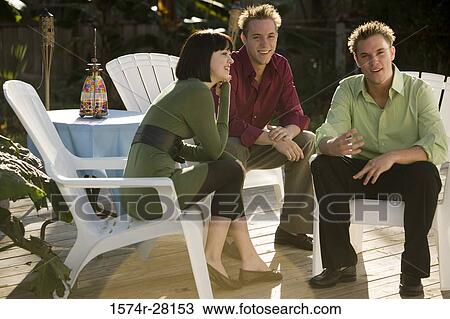 Cheerful friends sitting on armchairs on wooden deck View Large Photo Image Stock Image - Cheerful friends sitting on armchairs on wooden deck. Fotosearch