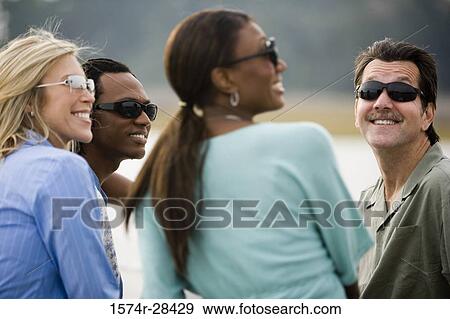Cheerful friends sitting together and looking away View Large Photo Image Stock Photo - Cheerful friends sitting together and looking away. Fotosearch