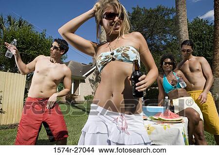Picture - Cheerful friends standing by table on lawn. Fotosearch