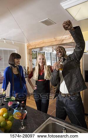 Cheerful friends standing in a kitchen with wines View Large Photo Image Stock Photo - Cheerful friends standing in a kitchen with wines. Fotosearch
