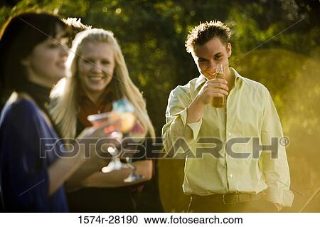 Stock Image - Cheerful friends with drinks outdoors. Fotosearch