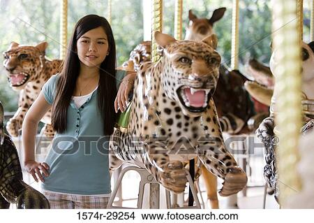 Cheerful girl standing in a carousel by a carousel leopard View Large Photo Image Picture - Cheerful girl standing in a carousel by a carousel leopard. Fotosearch