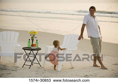 Stock Image - Cheerful man with daughter relaxing on the beach. Fotosearch
