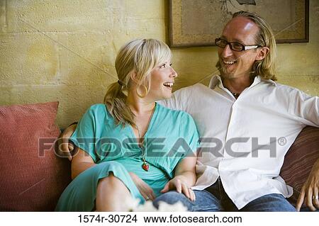 Cheerful mature couple sitting together on a sofa View Large Photo Image Picture - Cheerful mature couple sitting together on a sofa. Fotosearch