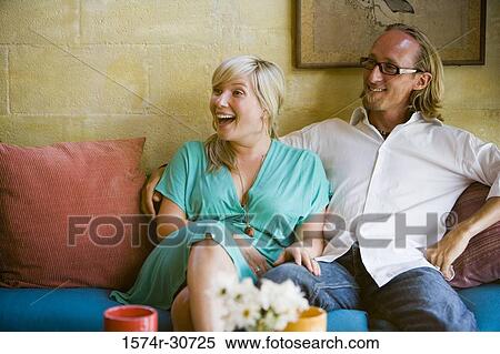 Cheerful mature couple sitting together on a sofa View Large Photo Image Stock Photography - Cheerful mature couple sitting together on a sofa. Fotosearch
