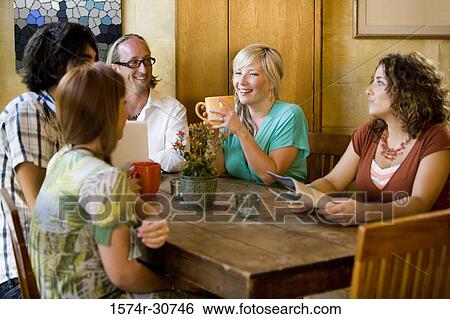 Stock Photograph - Cheerful mature woman sitting at table with her family. Fotosearch