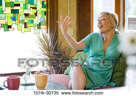 Cheerful mature woman sitting on a sofa and gesturing View Large Photo Image Stock Photography - Cheerful mature woman sitting on a sofa and gesturing. Fotosearch