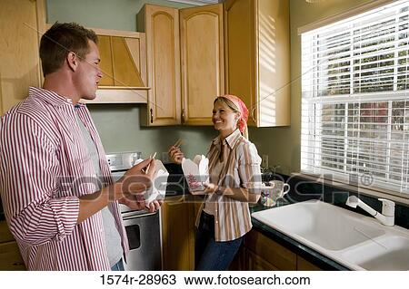Cheerful mid adult couple eating fast food in the kitchen View Large Photo Image Stock Image - Cheerful mid adult couple eating fast food in the kitchen. Fotosearch