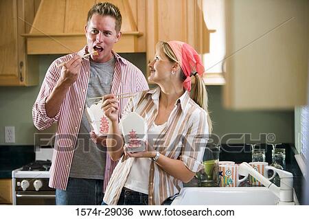 Cheerful mid adult couple eating noodles in the kitchen View Large Photo Image Stock Photograph - Cheerful mid adult couple eating noodles in the kitchen. Fotosearch