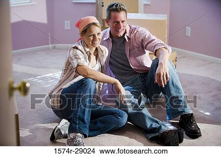 Cheerful mid adult couple sitting by cardboard boxes in a house View Large Photo Image Picture - Cheerful mid adult couple sitting by cardboard boxes in a house. Fotosearch