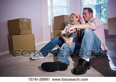 Cheerful mid adult couple sitting by cardboard boxes in a house View Large Photo Image Stock Image - Cheerful mid adult couple sitting by cardboard boxes in a house. Fotosearch