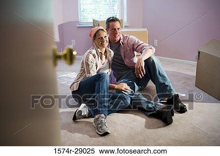 Cheerful mid adult couple sitting by cardboard boxes in a house View Large Photo Image Stock Photography - Cheerful mid adult couple sitting by cardboard boxes in a house. Fotosearch
