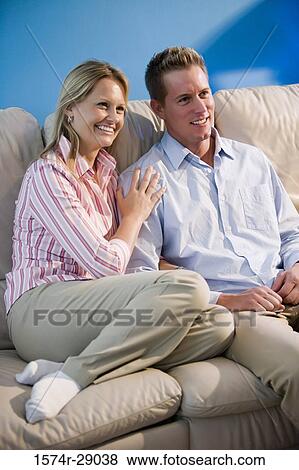 Stock Photo - Cheerful mid adult couple sitting on a sofa. Fotosearch