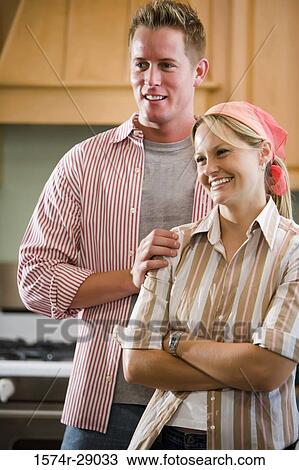 Cheerful mid adult couple standing by kitchen counter View Large Photo Image Stock Image - Cheerful mid adult couple standing by kitchen counter. Fotosearch