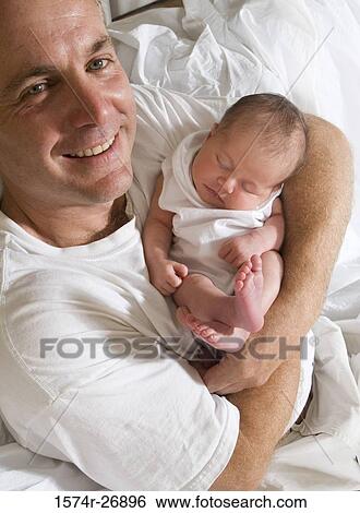 Stock Photograph - Cheerful mid adult man holding her baby. Fotosearch
