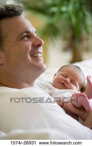 Cheerful mid adult man holding his baby View Large Photo Image Stock Image - Cheerful mid adult man holding his baby. Fotosearch