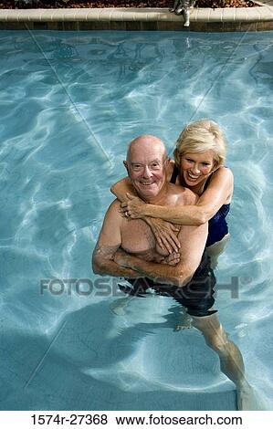 Cheerful senior couple embracing in swimming pool View Large Photo Image Stock Photo - Cheerful senior couple embracing in swimming pool. Fotosearch