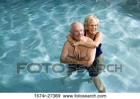 Cheerful senior couple embracing in swimming pool View Large Photo Image Stock Photo - Cheerful senior couple embracing in swimming pool. Fotosearch